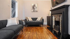 Ein Wohnzimmer mit Kamin, einer Couch und einem Fernseher, der ĂĽber dem Kamin angebracht ist.