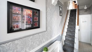Eine Treppe mit einem gemusterten Teppich, eine gerahmte Collage mit Sportmemorabilien an der Wand und ein kleiner Topfpflanzen am FuĂź.