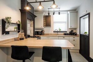 A modern kitchen with a central island, black chairs, and a backsplash with a geometric pattern. - Spacious 3-Bedroom House in Vibrant Liverpool – Your Perfect Getaway (Liverpool)