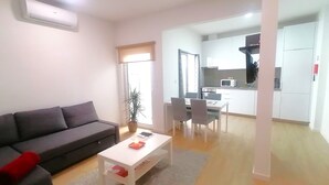 A modern living room with a sofa, a coffee table, and a dining area with chairs and a table. - CRISTIANO´S apartment with terrace in Alcochete (Alcochete)