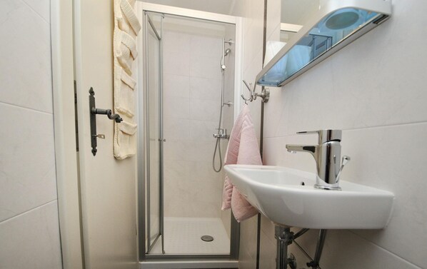 A modern bathroom with a glass-enclosed shower, a white sink, and a mirror above the sink. - Majestic Villa With Private Pool (Tinjan)