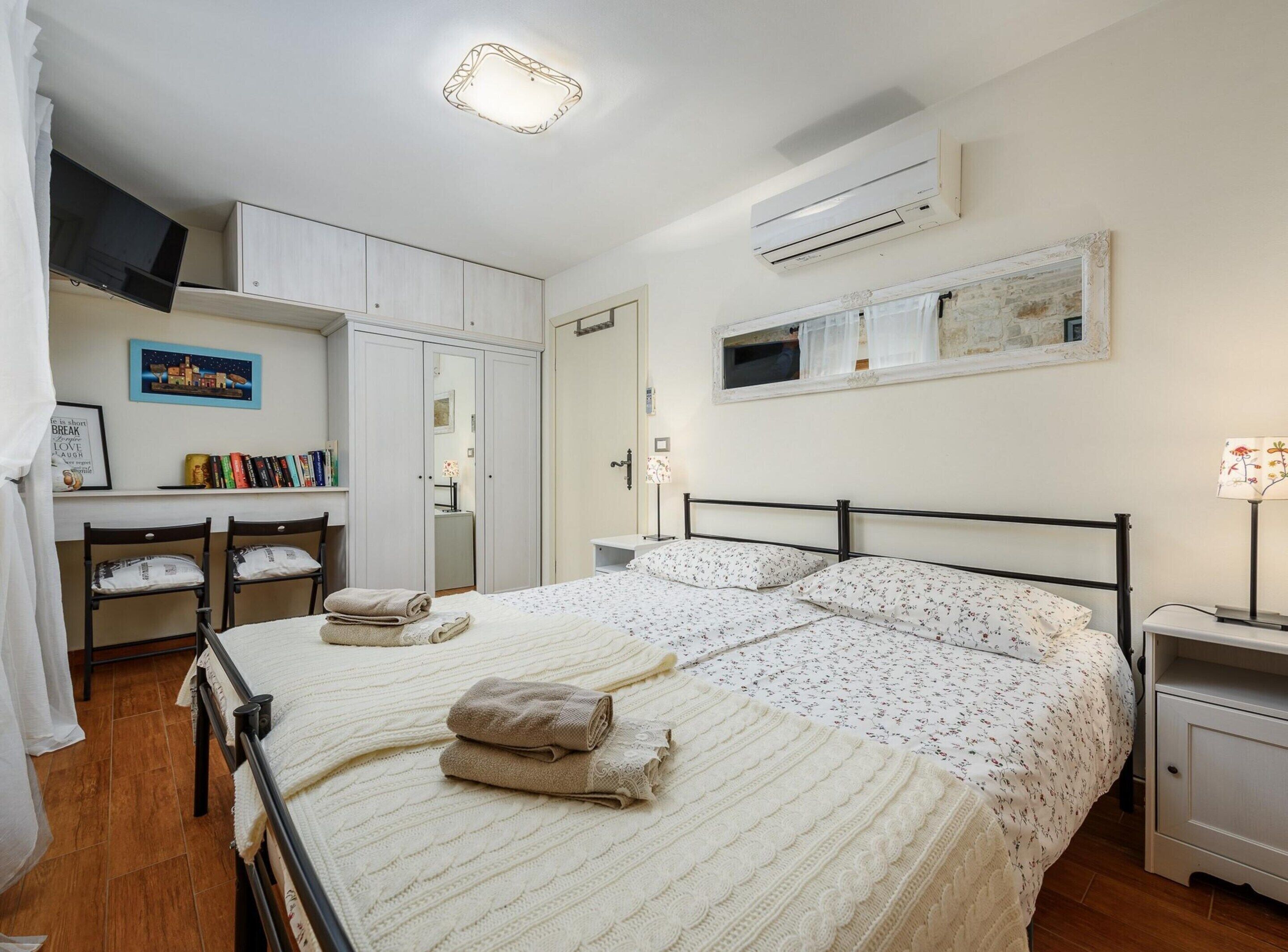 A bedroom with a bed, bedside tables, a desk, and a wardrobe.