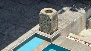 En swimmingpool med klart, blåt vand, omgivet af stenfliser og trin.