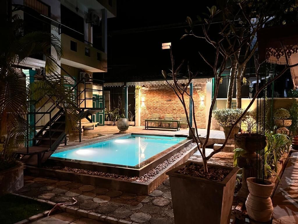 Una piscina rodeada de plantas en macetas y una escalera que lleva a un edificio.