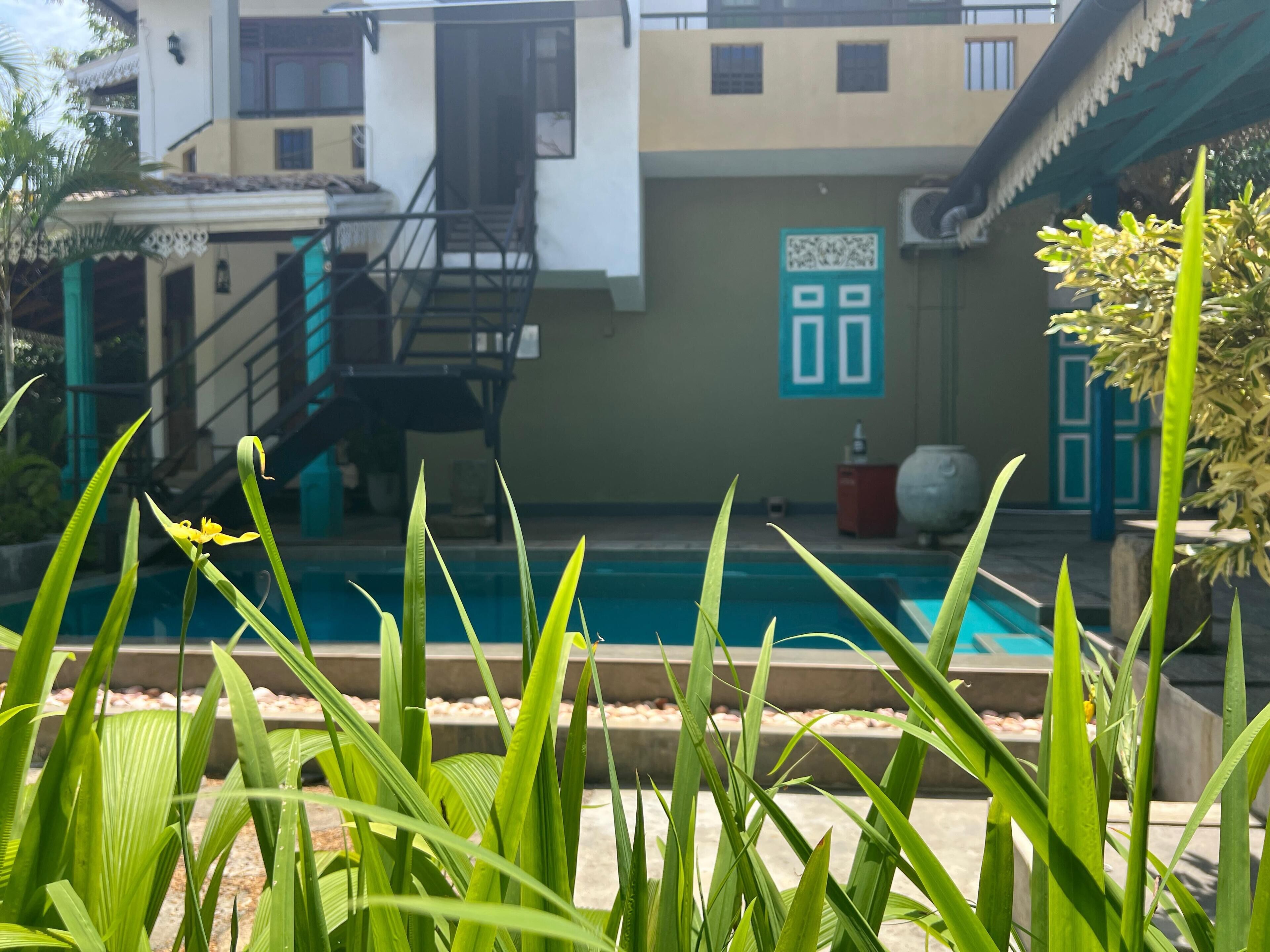 A swimming pool with a view of a building with a staircase and a door with a QR code.