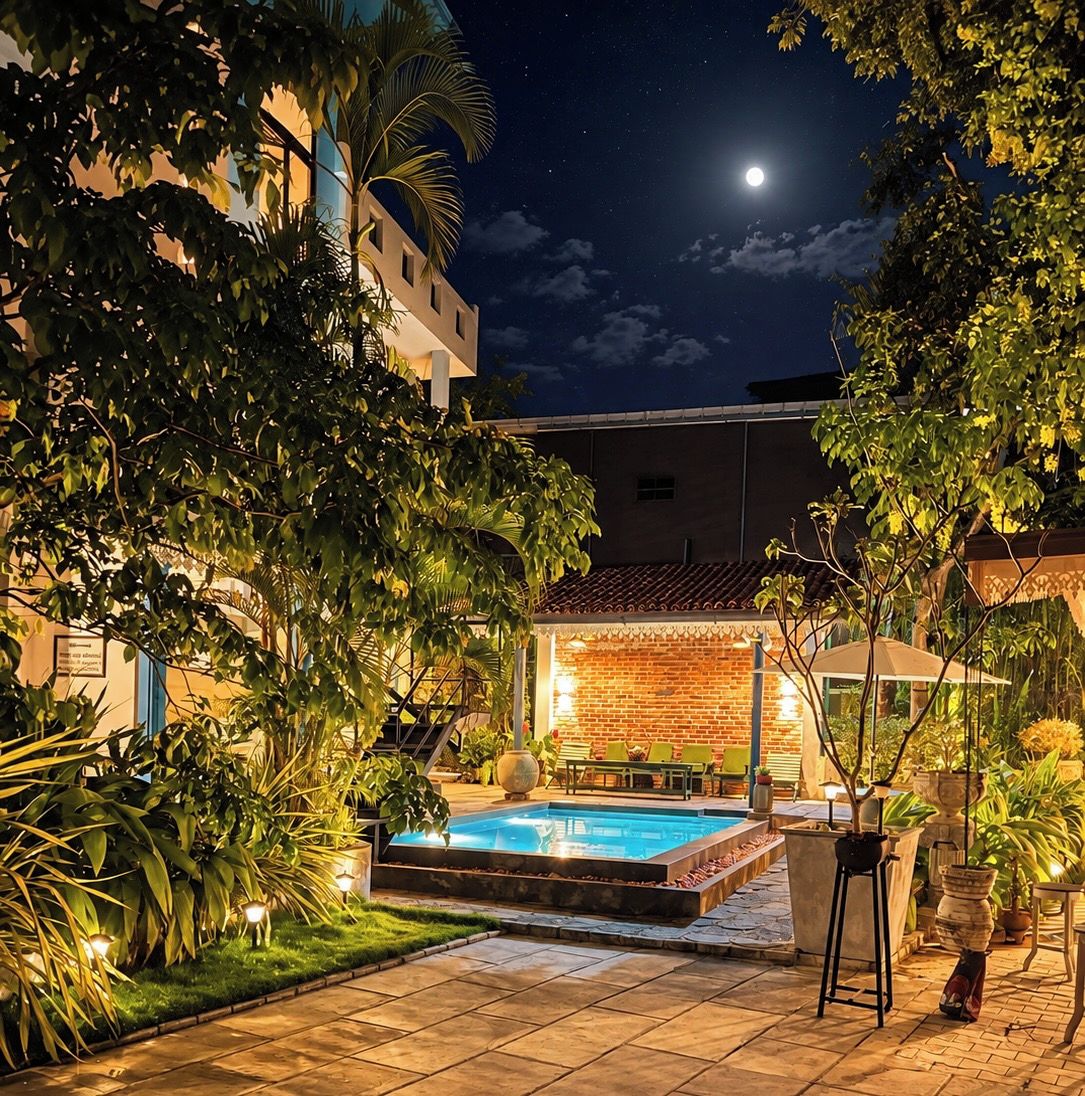 A nighttime outdoor pool area with a brick wall and a clear sky.