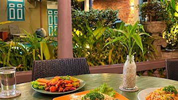 Un área de comedor al aire libre con varias mesas, cada una con una variedad de platos.