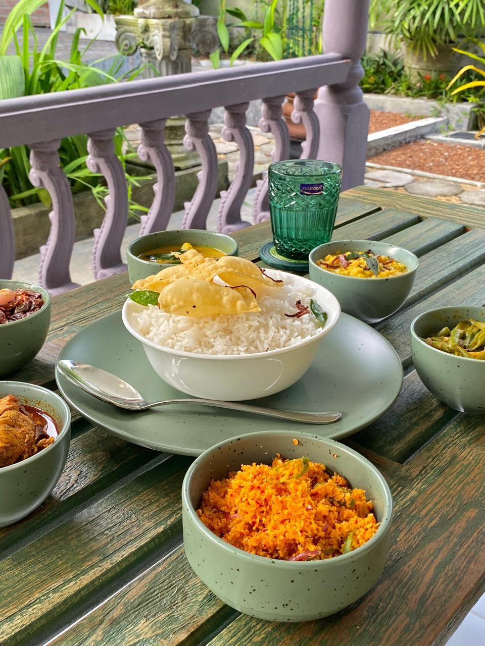 A table set with various dishes including rice, curry, and a bowl of what appears to be a vegetable dish.