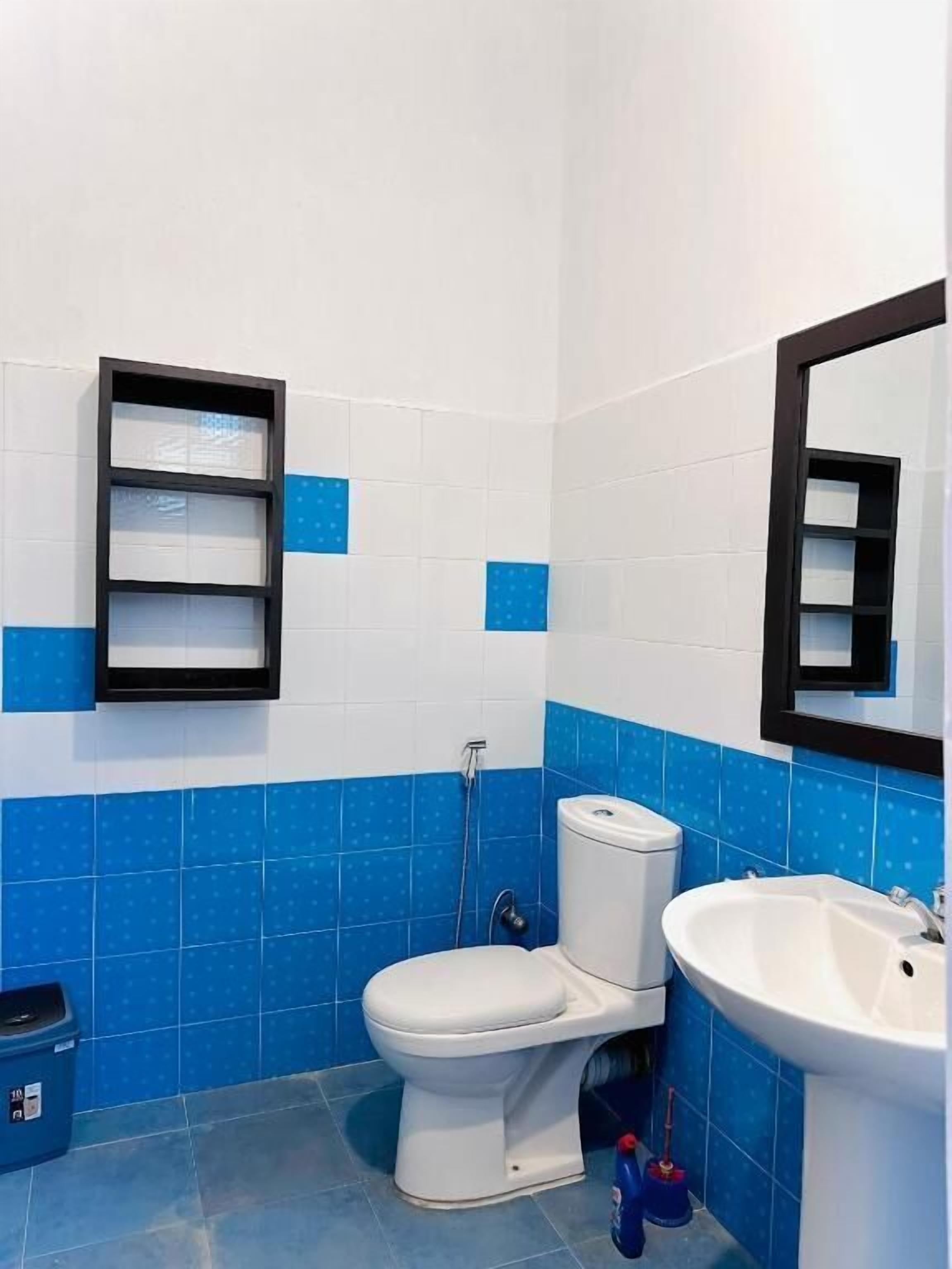 Un baño con inodoro, lavamanos y estantería.