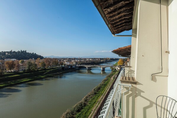 A river with bridges, a balcony with a railing, and buildings in the background. - Mamo Florence - Vespucci Apartment (Florence)
