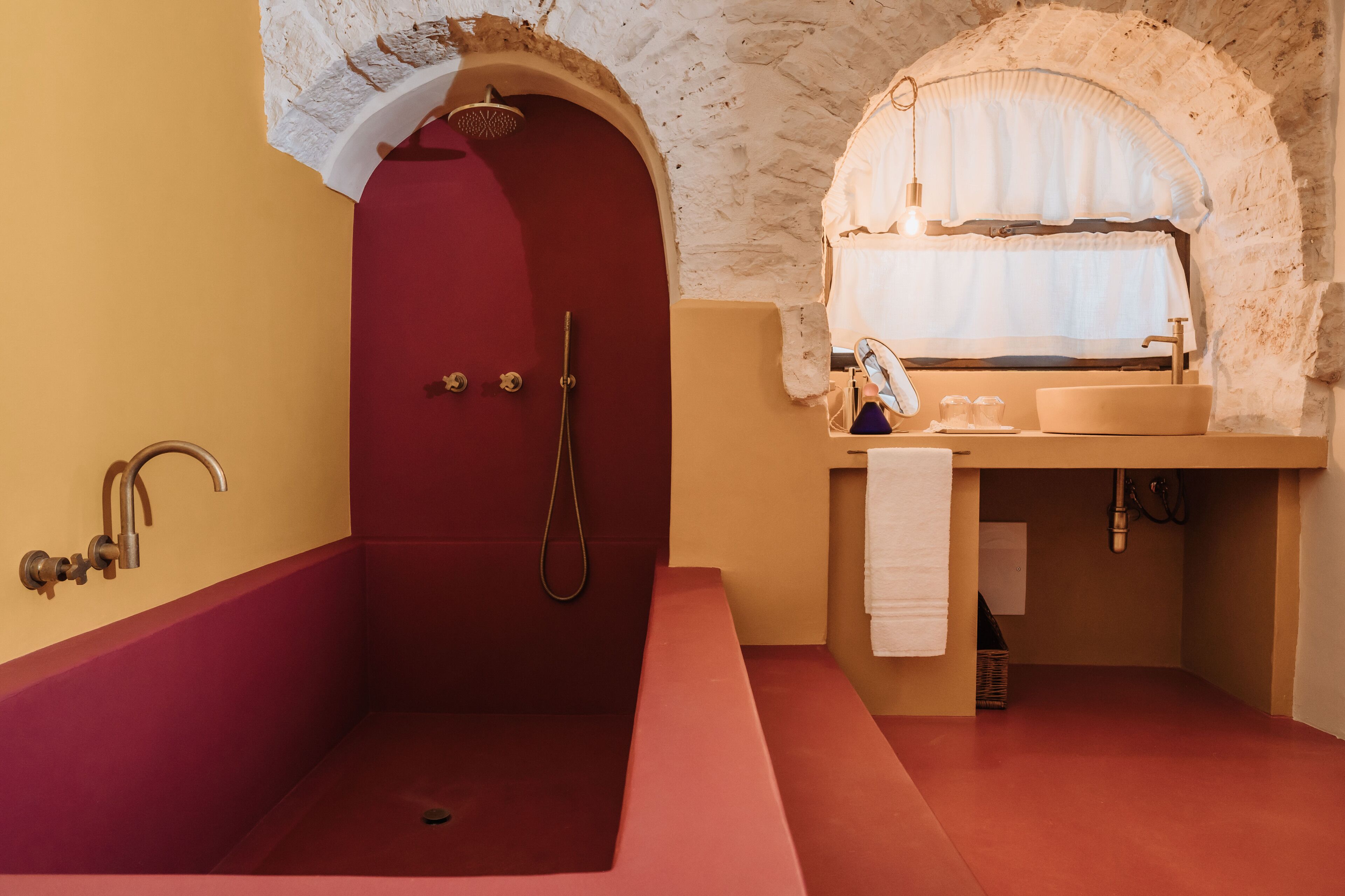 A bathroom with a red bathtub, a shower, and a sink with a mirror.