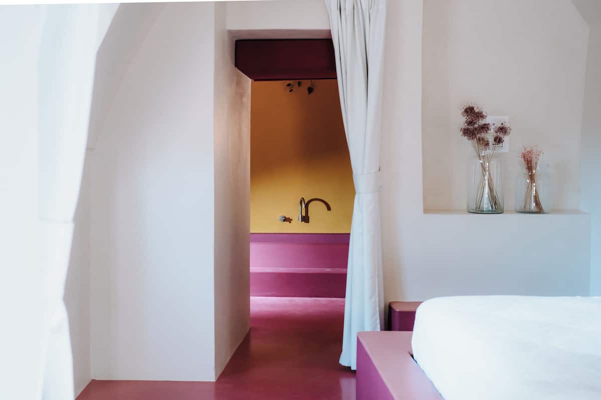 A bedroom with a bed, a bathroom with a sink, and a staircase.