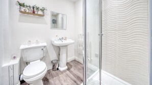 Ein modernes Badezimmer mit Toilette, Waschbecken und Duschbereich.