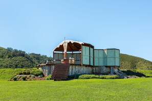 A rustic cabin with a wooden exterior, a porch, and a large window.