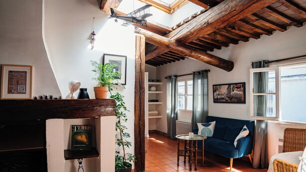 A cozy living room with a fireplace, a blue sofa, and a wooden ceiling. - Le Cardinale - A Journey to Provence (Aix en Provence)