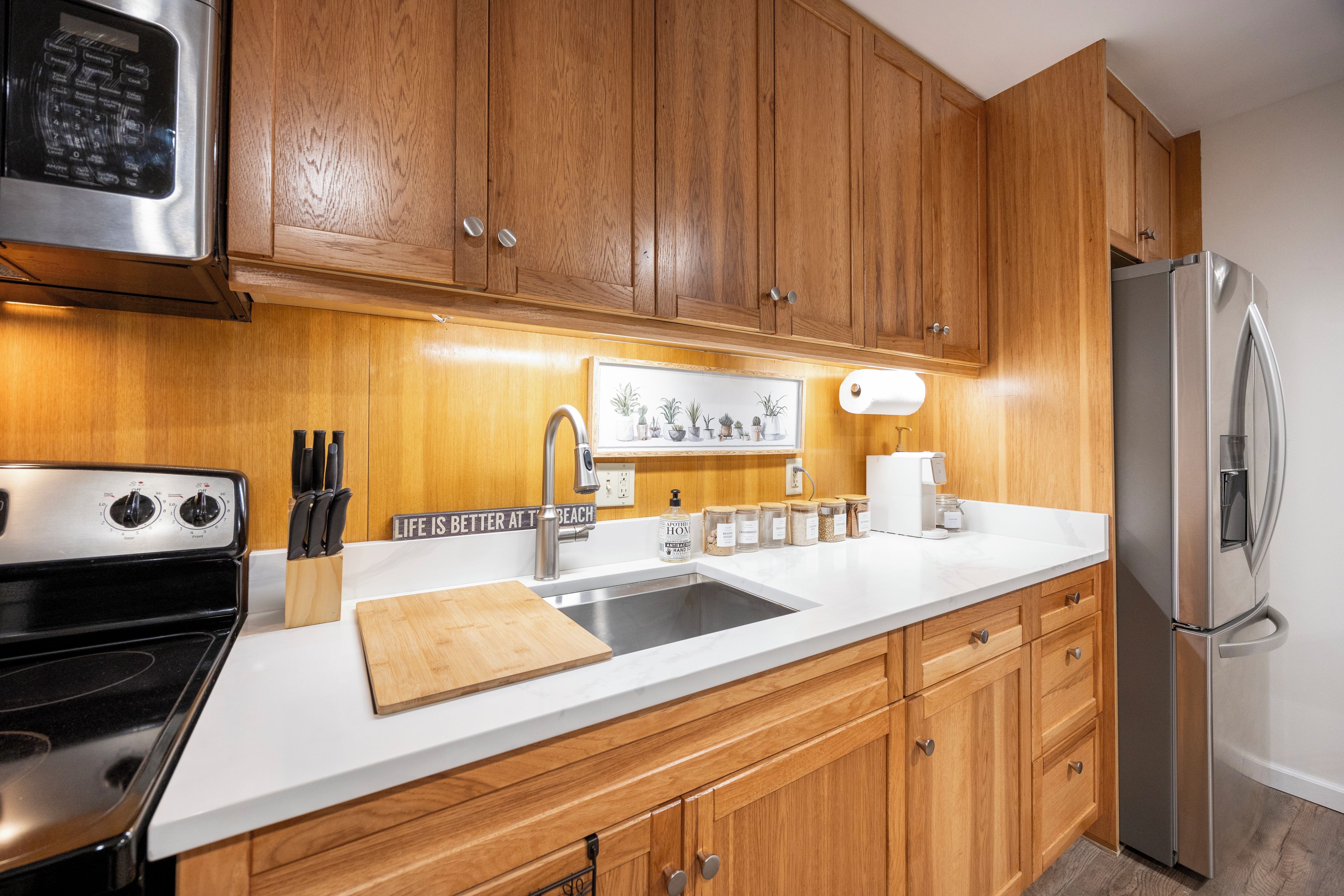 A kitchen with wooden cabinets, a stainless steel refrigerator, a sink, and a coffee maker.