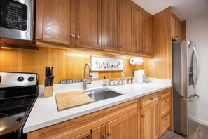 A kitchen with wooden cabinets, a stainless steel refrigerator, a sink, and a coffee maker.