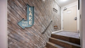 A staircase with wooden steps and a wall with a directional sign pointing to 'LAKE THIS WAY'. - Stunning Deluxe King Studio  #124 at Donner Lake Village (Truckee)