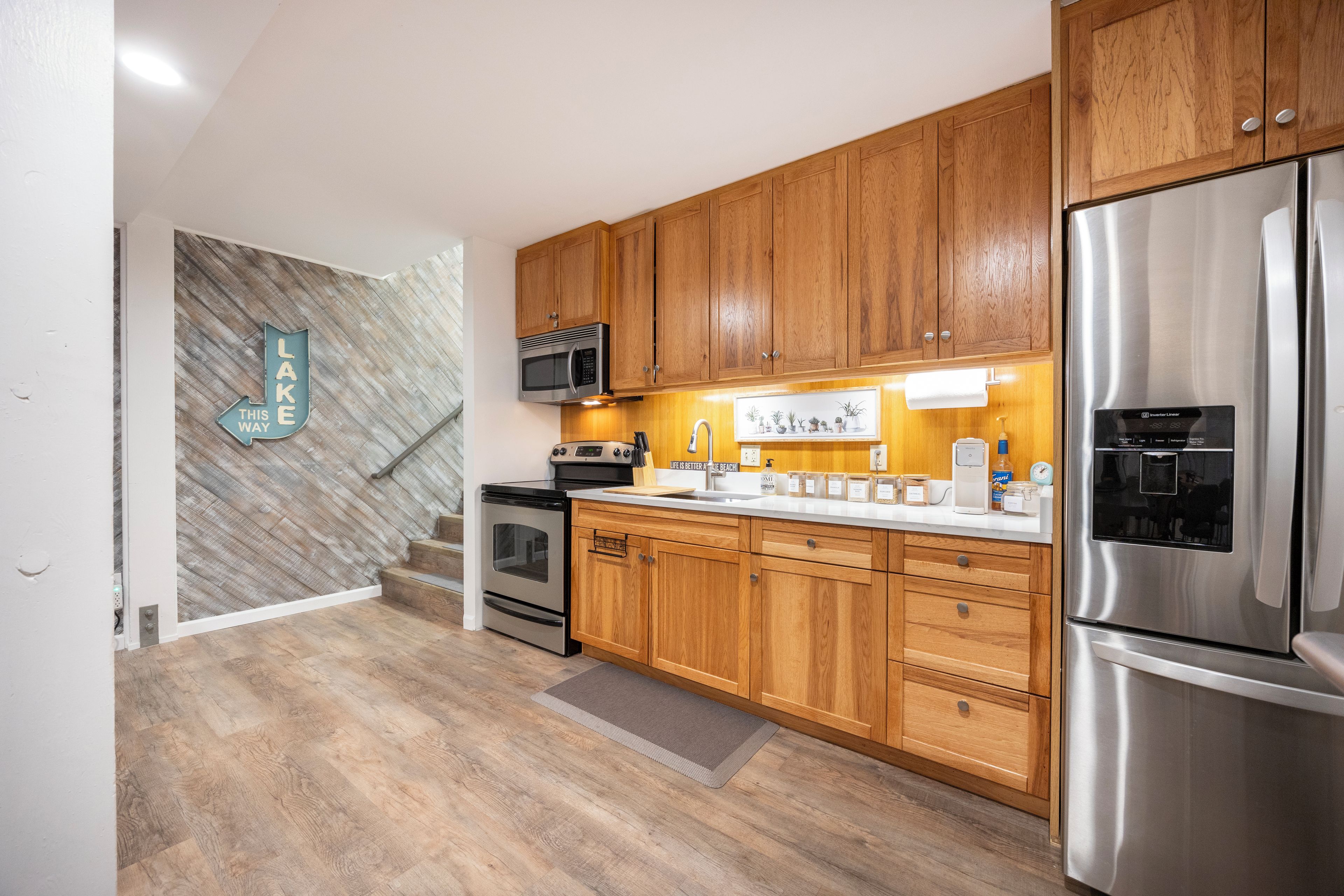 Una cocina moderna con armarios de madera, electrodomésticos de acero inoxidable y un revestimiento mural en patrón de espiga.