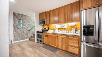 Una cocina moderna con armarios de madera, electrodomésticos de acero inoxidable y un revestimiento mural en patrón de espiga.
