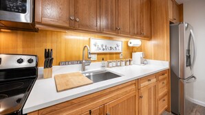 A kitchen with wooden cabinets, a stainless steel refrigerator, a sink, and a microwave. - Stunning Deluxe King Studio  #124 at Donner Lake Village (Truckee)