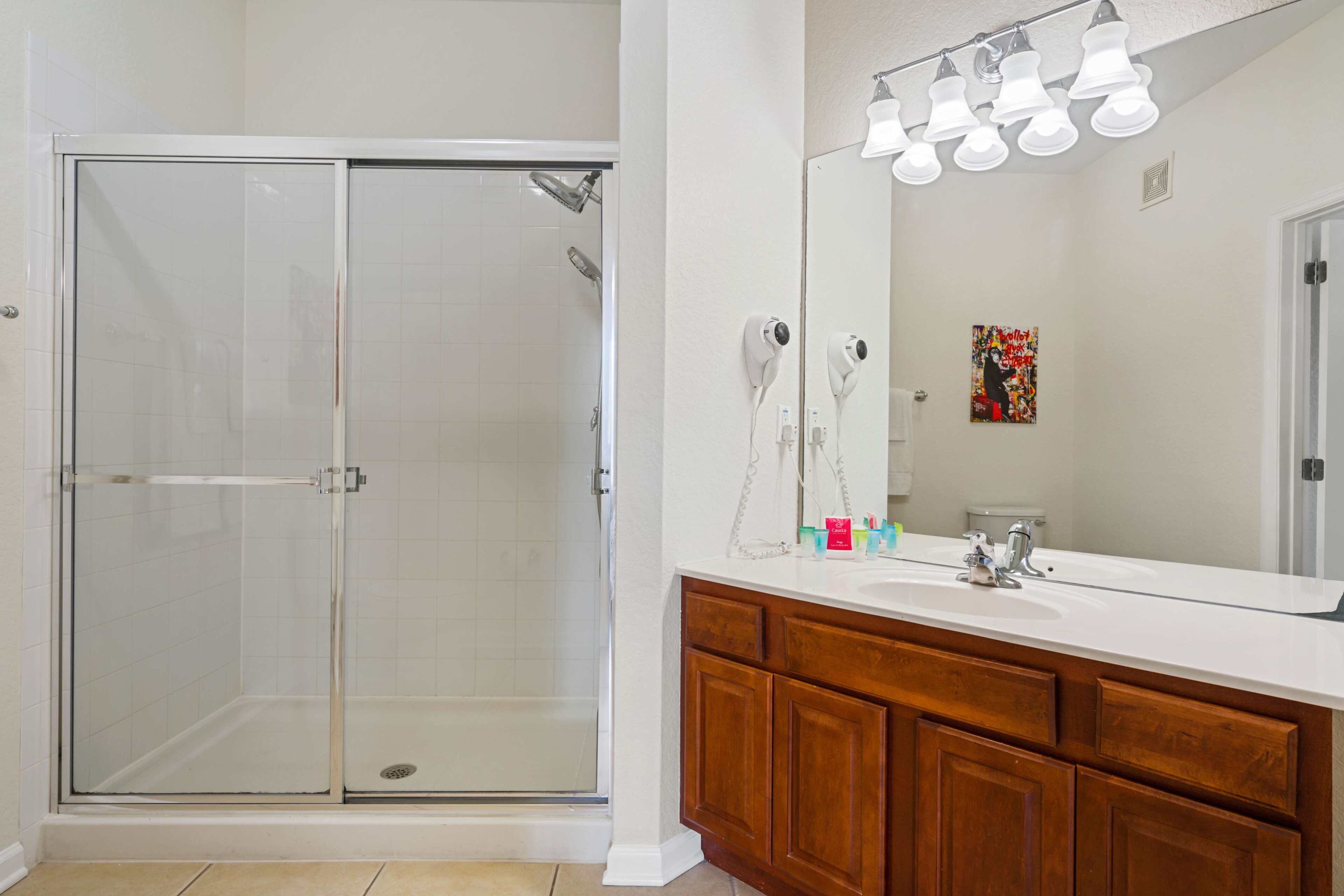 A bathroom with a glass-enclosed shower, a vanity with a mirror, and a light fixture above the mirror.