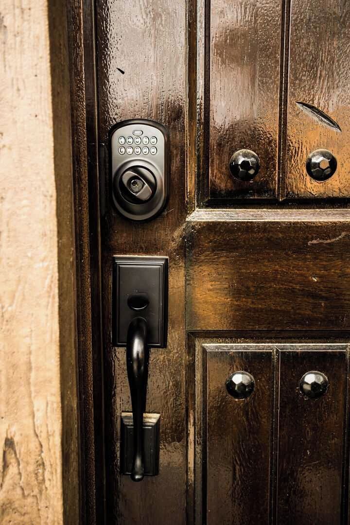 Una puerta de madera con una mirilla, un teclado numérico y un picaporte.