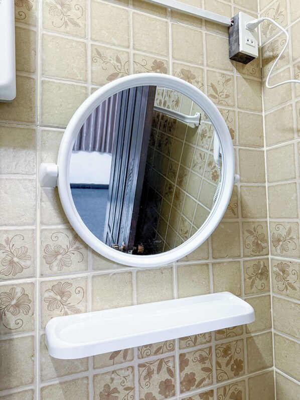 A bathroom with a round mirror, a white toilet, and a white shelf. - Lao Home (Vientiane)