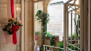 A balcony with potted plants, a red cloth, and a white railing. - Dimora Signorile by Wonderful Italy (Polignano a Mare)