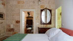 A room with a bed, a mirror, a fireplace, and a door leading to another room. - Dimora Signorile by Wonderful Italy (Polignano a Mare)