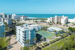 Ein Küstenhotel mit mehreren Gebäuden, einem Tennisplatz und Blick auf den Strand.