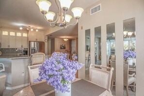 A spacious kitchen with modern appliances, a dining area with a table and chairs, and a chandelier.