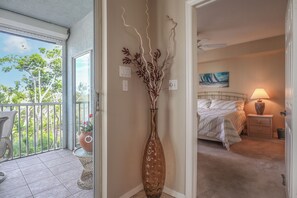 Una habitación con cama, mesita de noche, lámpara y un cuadro en la pared.