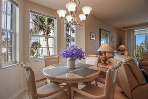A dining area with a round table, chairs, a vase with purple flowers, and a chandelier.