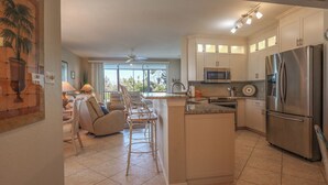 A spacious kitchen with a central island, stainless steel appliances, and a view to the outside.