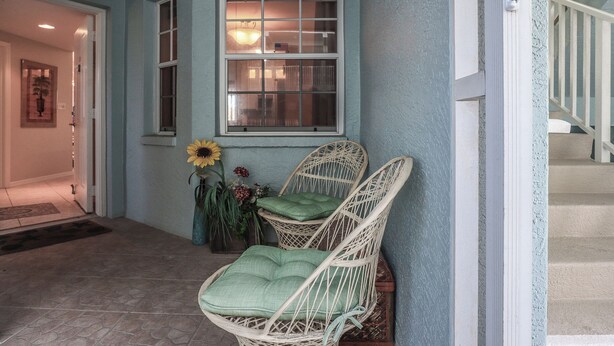 A hallway with a wicker chair, a window, and a door.