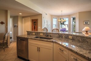 A kitchen with granite countertops, stainless steel appliances, and a large window providing natural light.