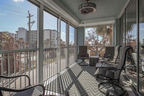 Un balcón con vista a edificios y árboles, amoblado con sillas y una mesa.