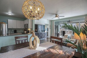 Una cocina moderna con comedor, que incluye una mesa de madera, sillas y una lámpara de techo de tejido original.