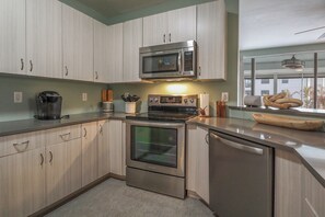 Una cocina moderna con electrodomésticos de acero inoxidable, armarios de madera y un ventanal que proporciona luz natural.