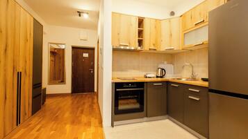 A modern kitchen with wooden cabinets, a stainless steel refrigerator, an oven, and a coffee maker.