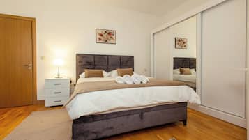Une chambre à coucher avec un grand lit, une table de chevet, une lampe, un miroir et une armoire.