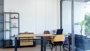 A modern office space with a wooden desk, black metal shelving, and a laptop.