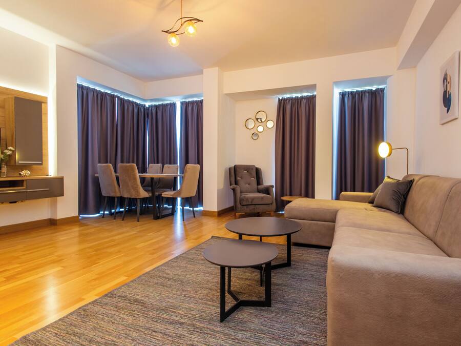 Una sala de estar moderna con un sofá, dos sillones, una mesa de centro y un comedor con mesa y sillas.