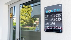 Ein schwarzes Schild mit dem Namen "RONDO" und einer Liste von Telefonnummern an einer weißen Wand.