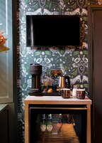 Una kitchenette con cafetera, tazas y refrigerador.