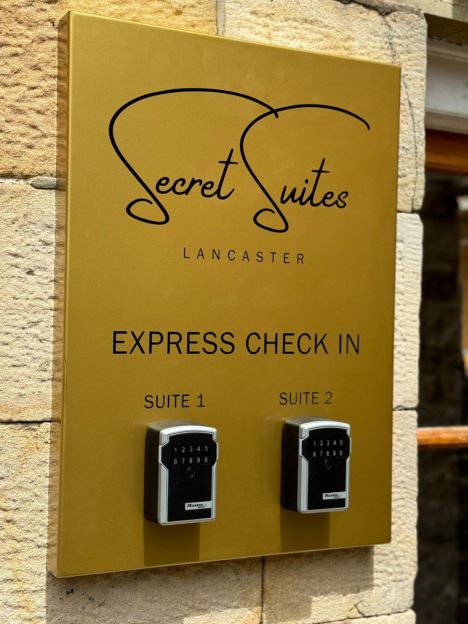 A sign for 'Secret Suites' in Lancaster indicating 'Express Check In' for 'Suite 1' and 'Suite 2' with MasterCard and Visa card readers.