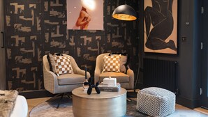 Un salon moderne avec deux fauteuils, une table basse ronde et un mur décoré d’un motif.