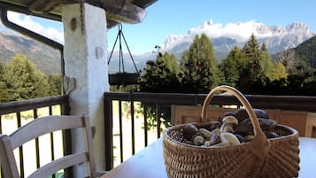A wicker basket filled with mushrooms on a wooden table, with a mountain view in the background.
