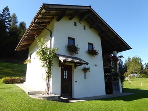 A traditional chalet with a sloped roof, a wooden front door, and flower boxes on the windows. - Baita Mountain View Pale San Martino (Primiero San Martino di Castrozza)